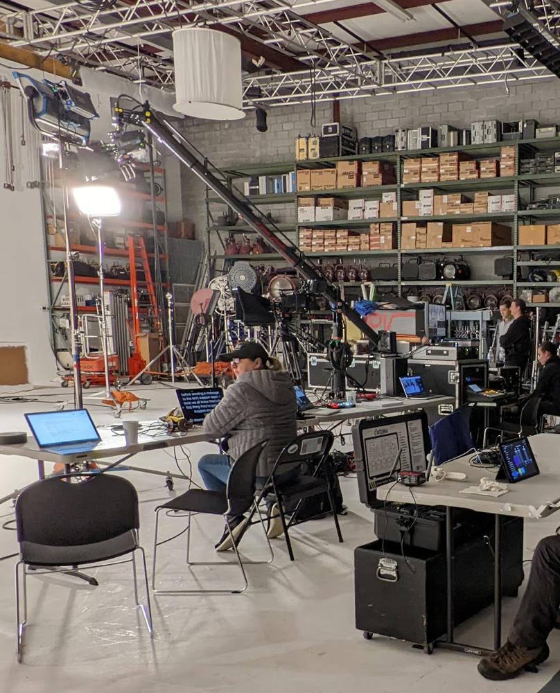 A studio production set with lighting, monitors, and crew workstations